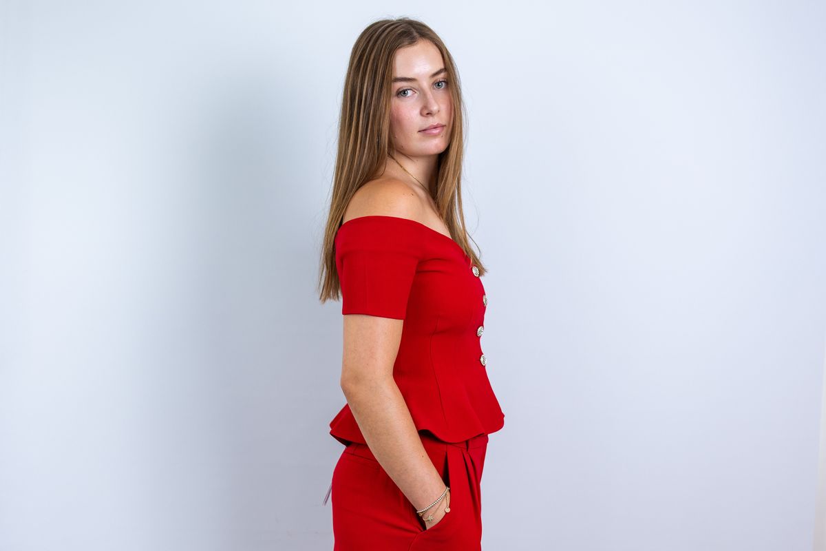 Portraitaufnahme im Studio: junge Frau in rotem Anzug vor hellem Hintergrund